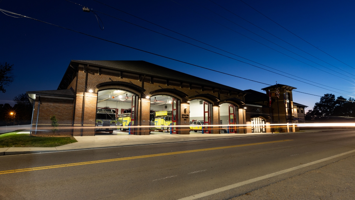 Exterior of the Ashland City Fire Department station illuminated at night with red traffic light trails