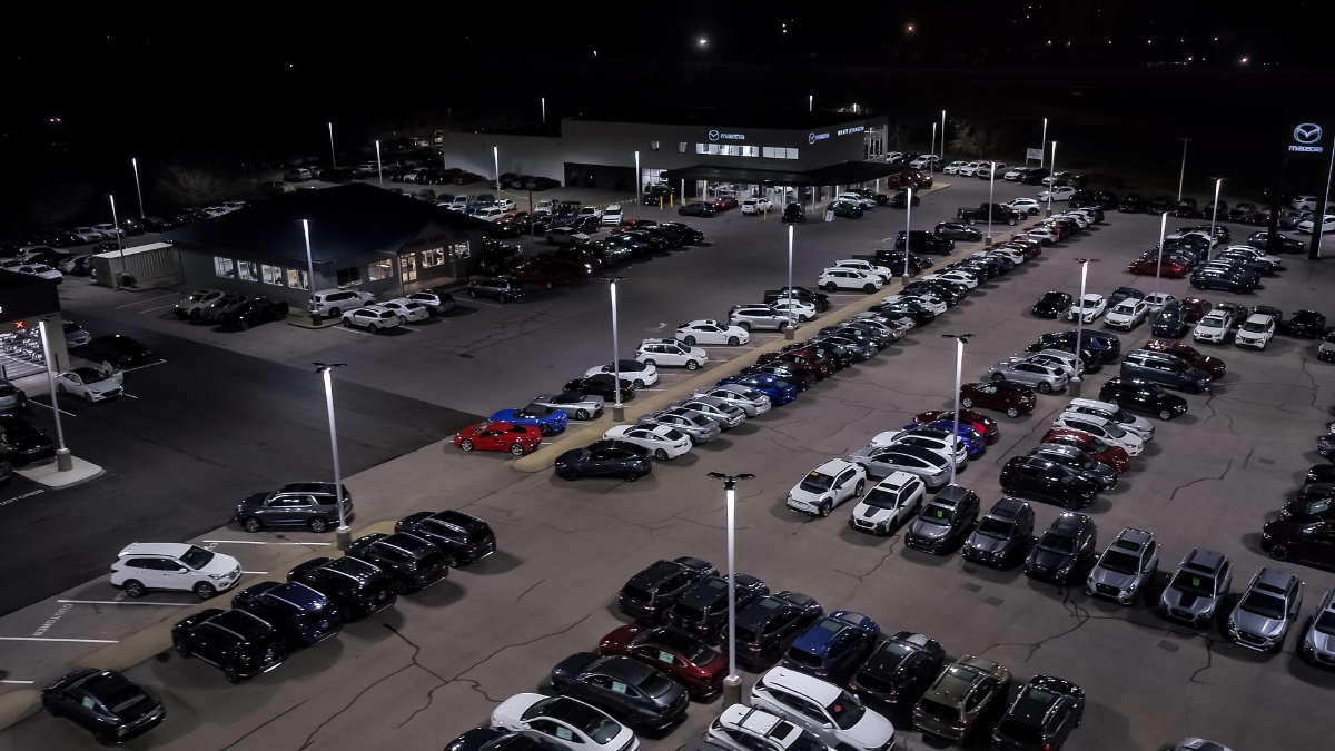 Aerial view of an illuminated car dealership parking lot at night
