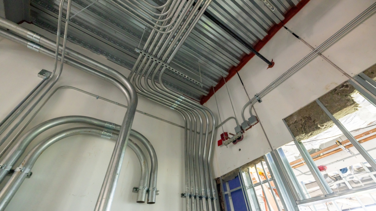 Commercial electrical conduit installed along the wall and metal ceiling deck