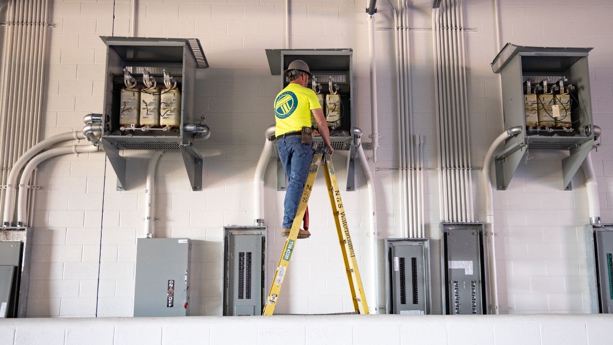 Commercial electrician installing electrical equipment at the Wyatt Johnson Subaru construction site