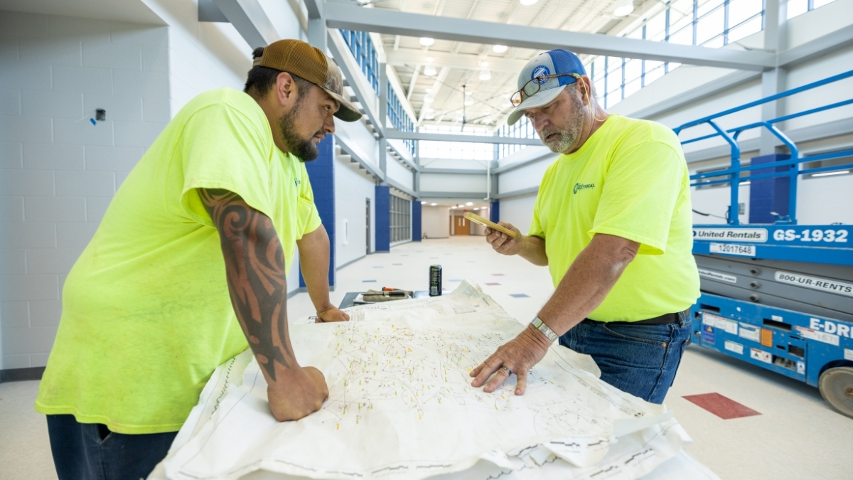 Two commercial electricians reviewing electrical plans at a school construction project