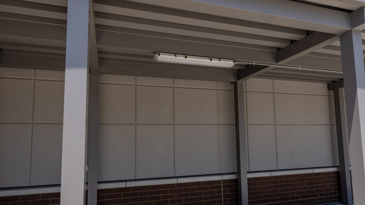 Exterior commercial light fixture installed beneath a steel building canopy