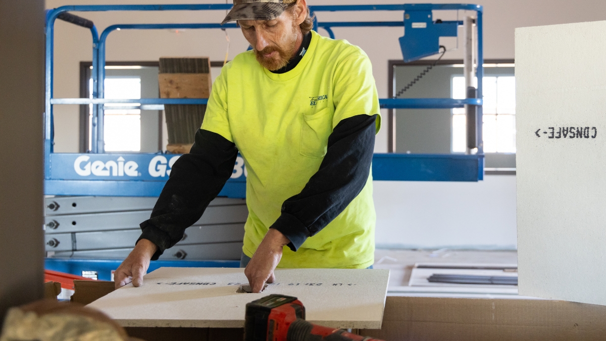 Construction worker measuring and cutting a suspended ceiling tile