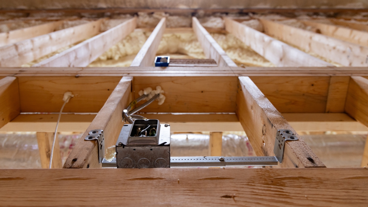 Electrical junction box and conduit installed between wood ceiling joists