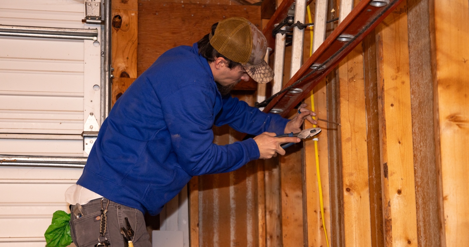 Electrician holding pliers installing wiring in garage