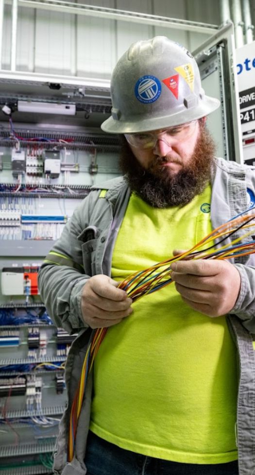 Electrician holding wires at industrial facility