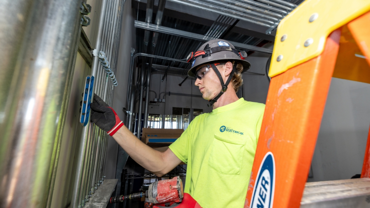 Electrician leveling and installing metal conduit at a commercial construction site