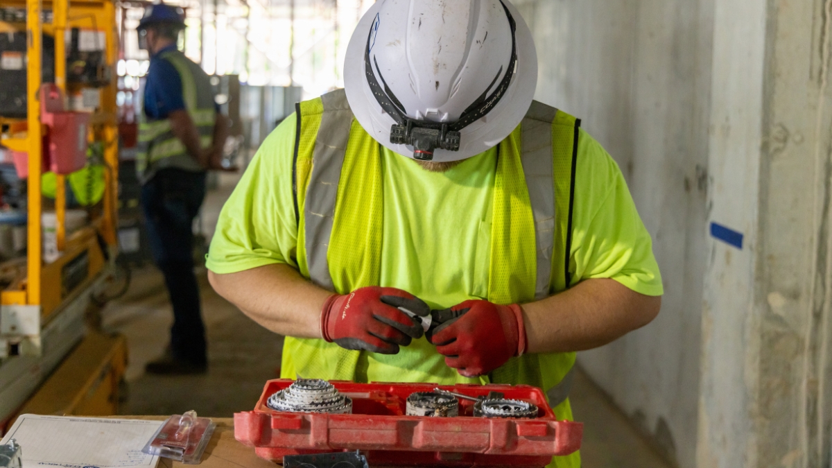 Commercial electricians installing overhead conduit and reviewing plans at a construction site