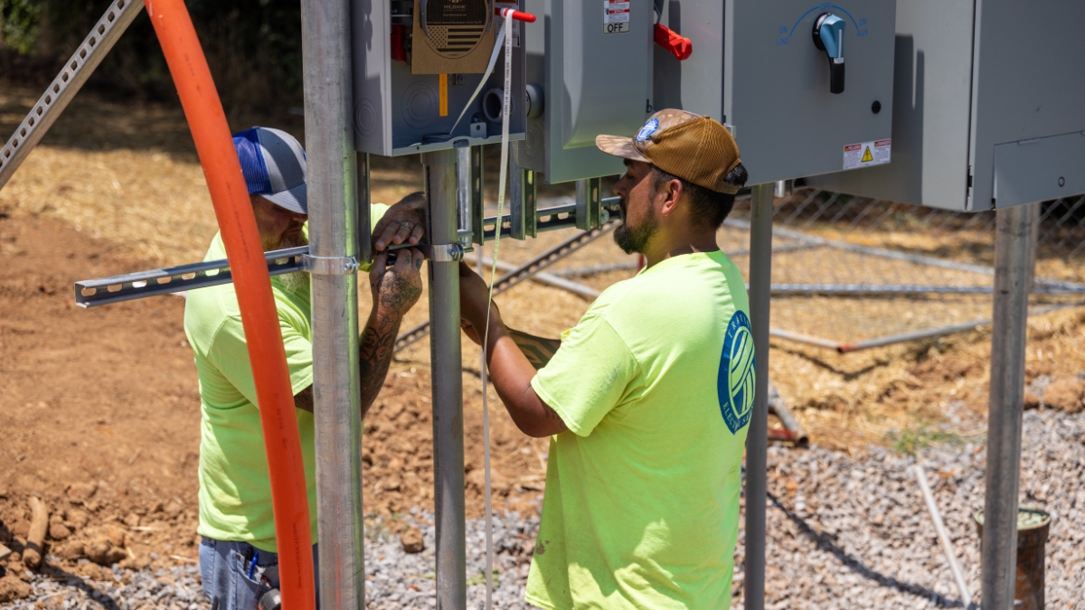 Electricians installing outdoor commercial electrical equipment and conduit