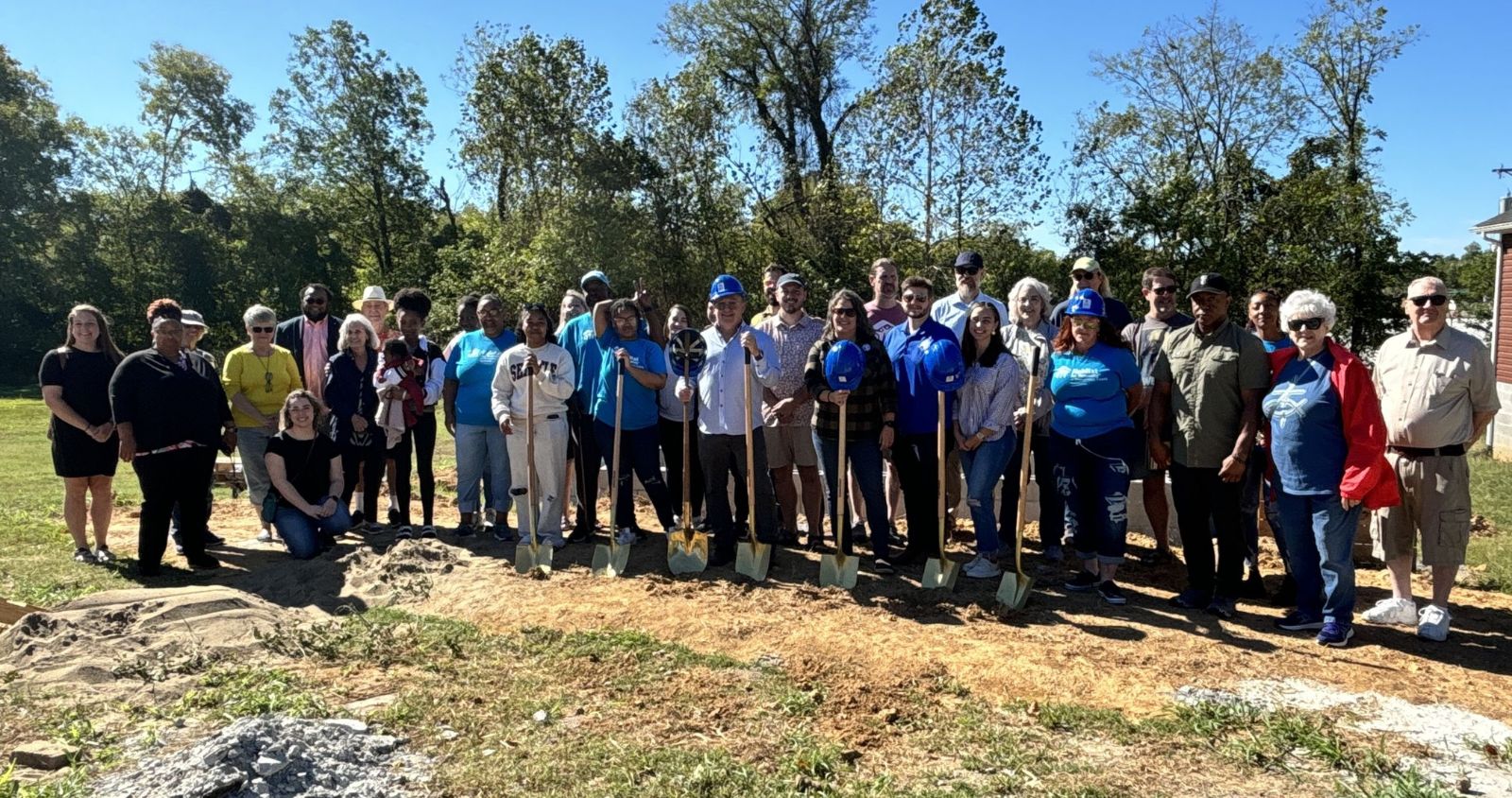 several people holding shovels at a groundbreaking ceremony with others standing around them