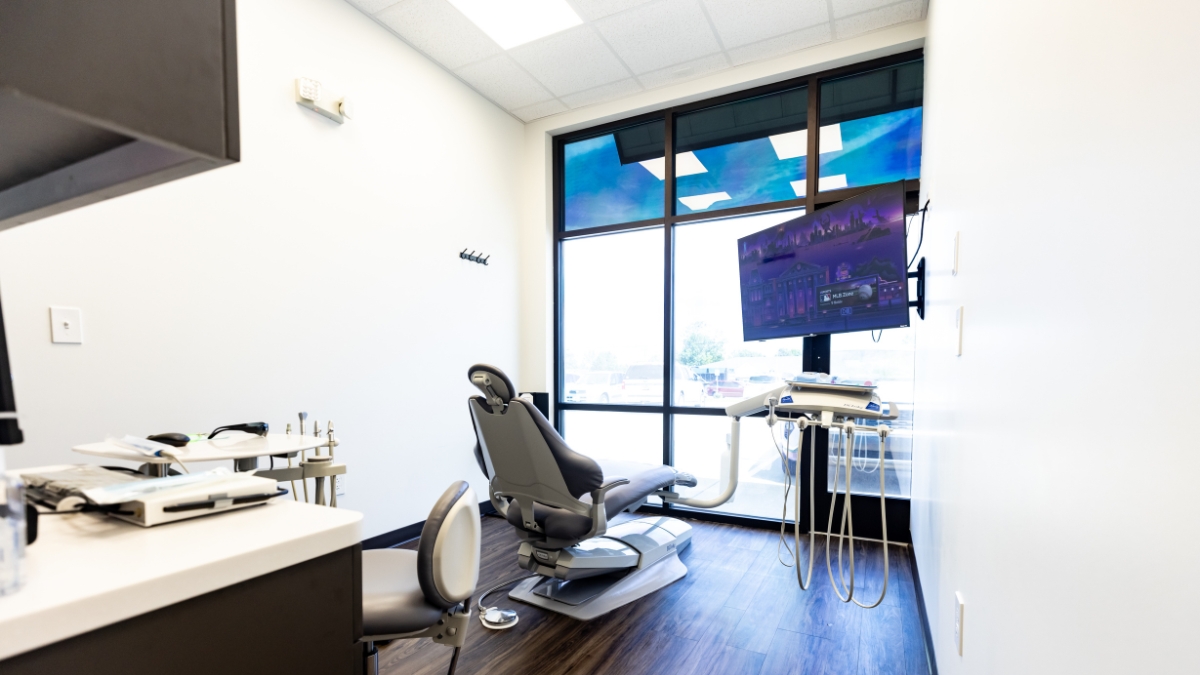 Modern Ironwood Dental treatment room with dental chair, equipment, television and large window