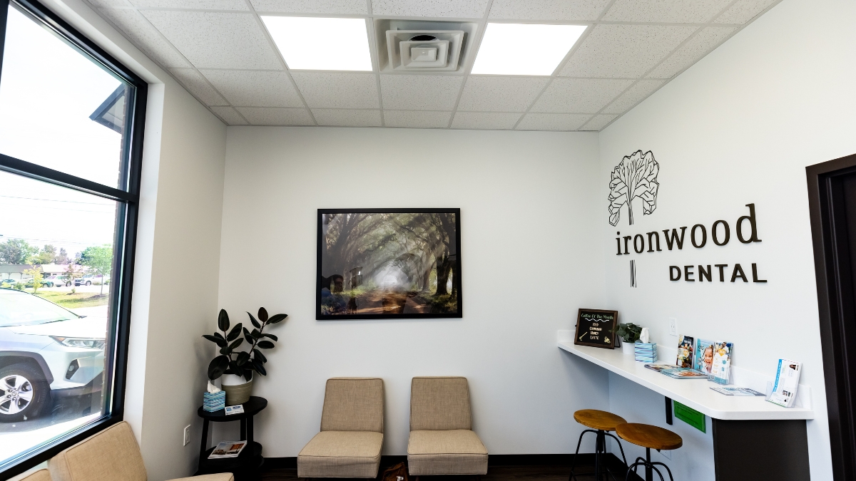 Ironwood Dental waiting room with seating, wall logo, reception counter and large window