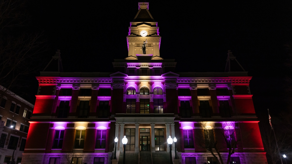 Montgomery County Courthouse illuminated with purple, red and gold lights at night