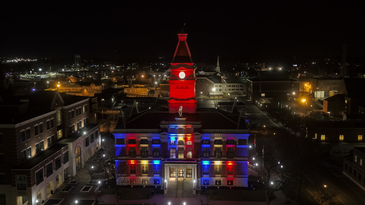 Wide aerial view of the Montgomery County Courthouse illuminated in colorful patriotic lights