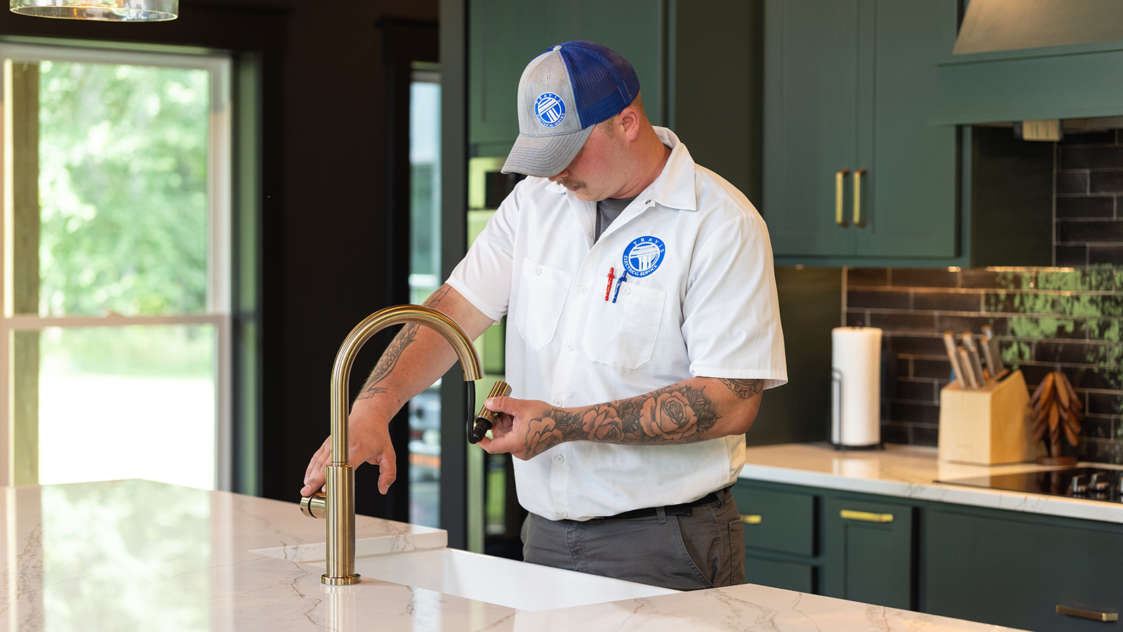 Plumber doing a faucet repair at a kitchen island sink with running water.