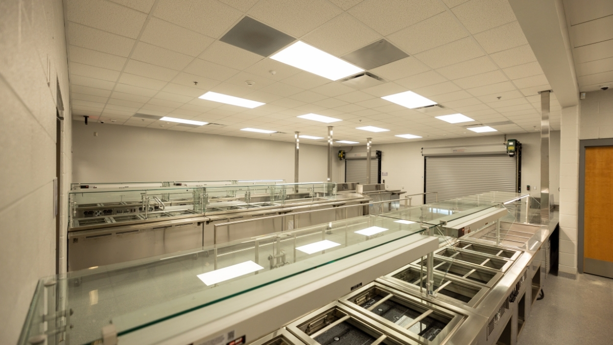 School cafeteria serving area with stainless steel food stations and glass sneeze guards