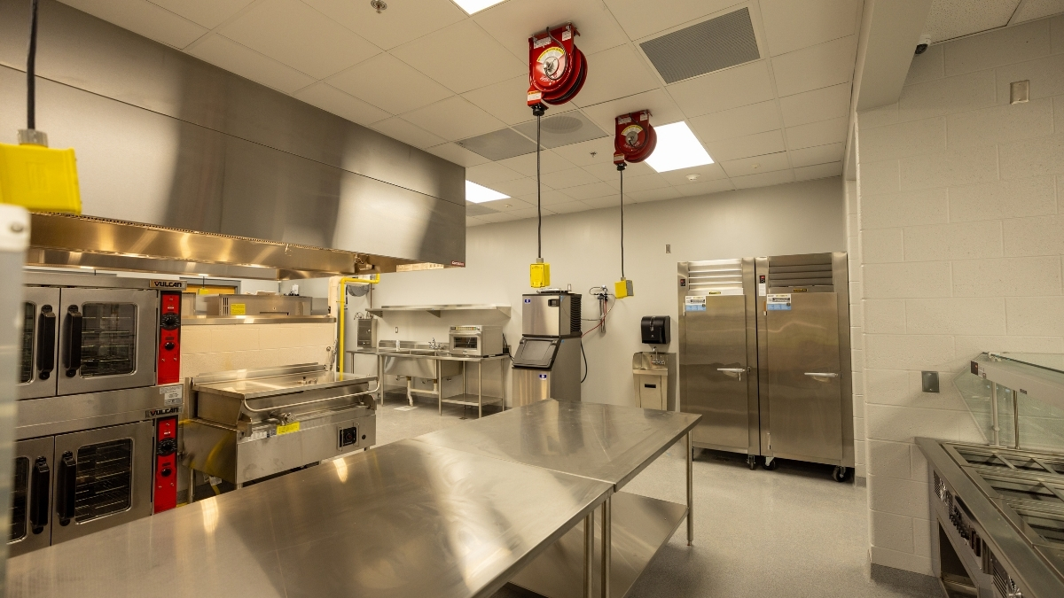Commercial school kitchen with stainless steel ovens, refrigerators and preparation tables