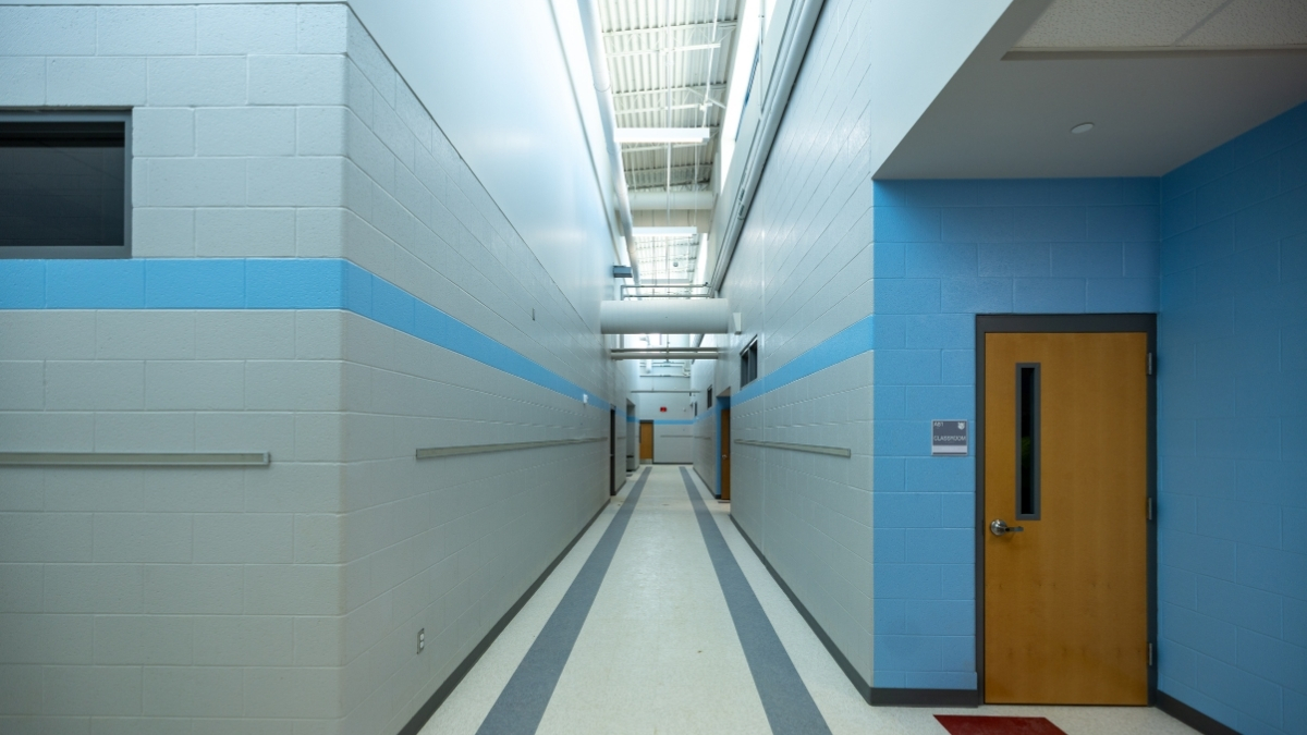 Bright school hallway with blue accent walls, classroom doors and overhead lighting
