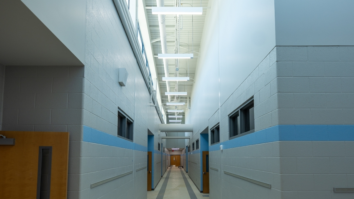 School hallway with blue wall accents, classroom doors and natural light from above